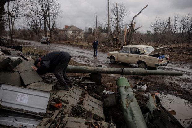 ocal man looks into a Russian tank left behind after Ukrainian forces expelled Russian soldiers