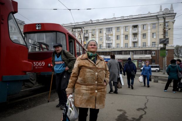 People wait for a tram outside the main railway station in the central Ukrainian city of Dnipro, where a city official said the day before that the remains of more than 1500 Russian soldiers are being kept in its morgues, on April 15, 2022 during the war in Ukraine. - Russia's defence ministry warned today it will intensify attacks on the Ukrainian capital Kyiv in response to strikes on Russian soil, after accusing Ukraine of targeting Russian border towns. (Photo by Ed JONES / AFP)