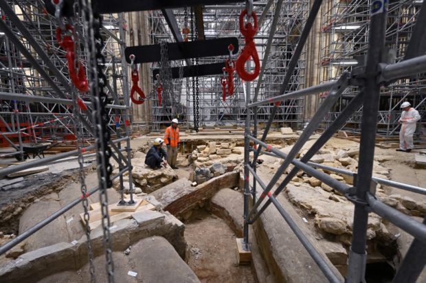 Workers stand among scaffolding of construction and renovation work, on the site of the discovery of a 14th century sarcophagus, inside the Notre-Dame cathedral in Paris on April 15, 2022, on the third anniversary of a fire that partially destroyed the cathedral. (Photo by Bertrand GUAY / AFP)