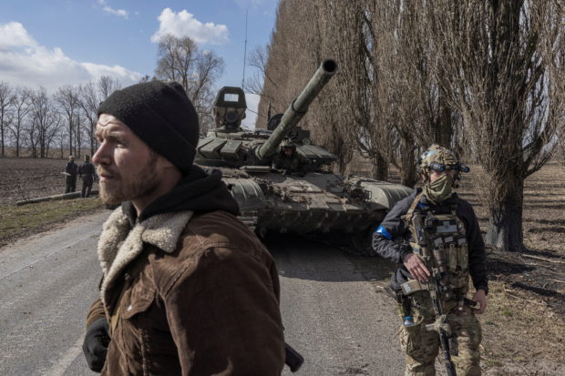 Ukrainian servicemen walk past a Russian tank captured after fighting with Russian troops in the village of Lukyanivka outside Kyiv, as Russia's invasion of Ukraine continues, Ukraine, March 27, 2022. REUTERS/Marko Djurica