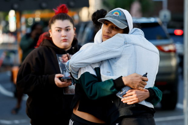People hug near the crime scene after an early-morning shooting in a stretch of downtown near the Golden 1 Center arena in Sacramento, California, U.S. April 3, 2022. REUTERS/Fred Greaves