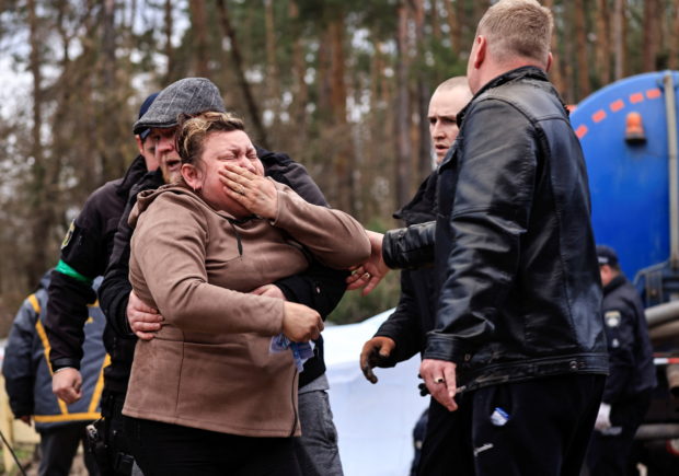 A mother reacts as police members exhume the body of her son, who according to the head of the village was killed by Russian soldiers, from a well at a fuel station in Buzova, Kyiv region, Ukraine April 10, 2022. REUTERS/Zohra Bensemra
