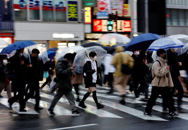 FILE PHOTO: Pedestrians wearing protective face masks, amid the coronavirus disease (COVID-19) pandemic, walk at a shopping district on the first day after the lifting of COVID-19 restrictions imposed on Tokyo and 17 other prefectures, in Tokyo, Japan, March 22, 2022. REUTERS/Kim Kyung-Hoon
