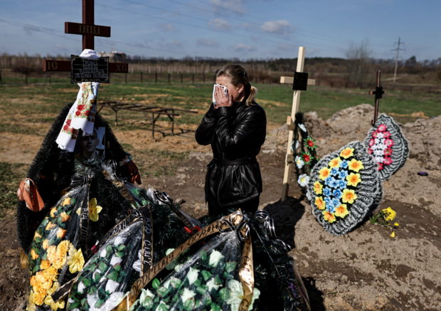 Irina Tromsa, 50,   who said her son Bohdan Tromsa, 25, a territorial defence member, was killed by Russian troops on the frontline near Sumy, wipes her tears with a handkerchief as she mourns by his grave day after his burial at the cemetery in Bucha, amid Russia's invasion of Ukraine, Kyiv region, Ukraine April 24, 2022. REUTERS/Zohra Bensemra