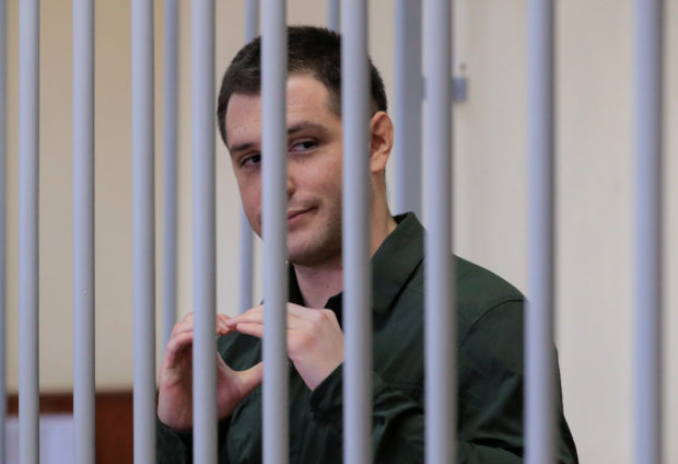 U.S. ex-Marine Trevor Reed, who was detained in 2019 and accused of assaulting police officers, gestures inside a defendants' cage during a court hearing in Moscow, Russia March 11, 2020. REUTERS/Tatyana Makeyeva