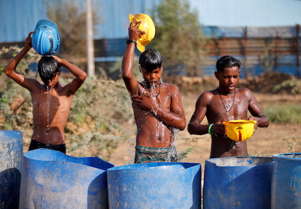Workers use their helmets to pour water to cool off near a construction site on a hot summer day on the outskirts of Ahmedabad. STORY: Temperatures break monthly records in India. STORY: Temperatures break monthly records in India under heat wave