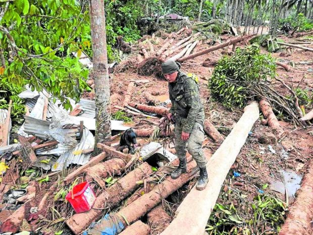 A soldier and his dog on April 18 search through the rubble hoping to find residents who went missing after a landslide hit Barangay Kantagnos in Baybay City on April 10, 2022. STORY: Leyte village hit hard by Agaton off-limits