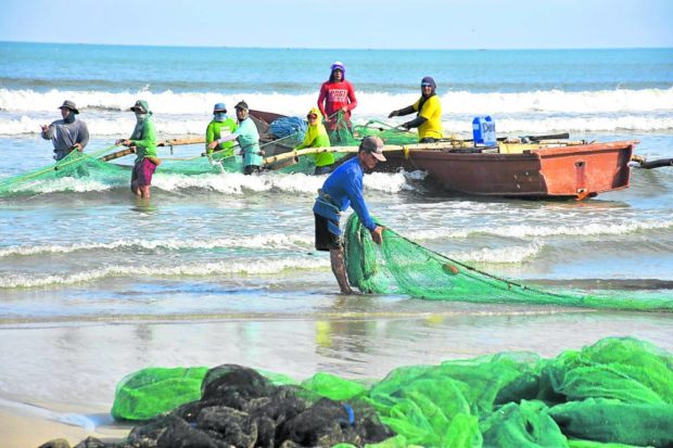 Fishermen in Binmaley, Pangasinan, check their net after a successful catch in Lingayen Gulf on March 19