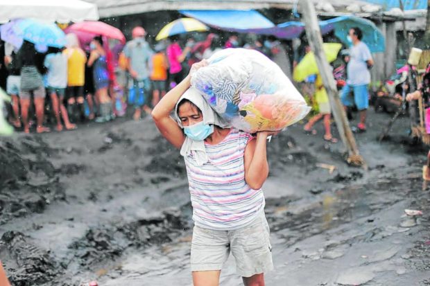 A resident of Camalig, Albay, carries a pack of clothes for her family