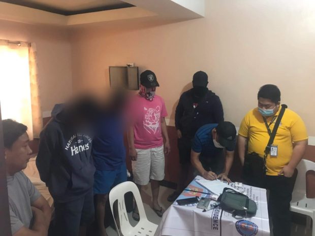 Plainclothes police officers inspect the pieces of evidence seized from the two suspects who were arrested during a drug buy-bust operation in Mabalacat City, Pampanga province on Tuesday, April 19