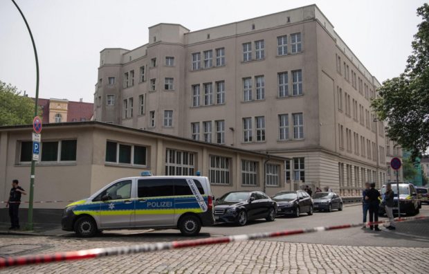 Police are seen behind a cordoned-off area in front of the building of the Lloyd Gymnasium, a secondary school in Bremerhaven, northern Germany on May 19, 2022, after shots were fired at the school. - One person was injured on May 19 after shots were fired at the secondary school in the northern city of Bremerhaven, police said, adding that they had arrested the suspected gunman. The injured person was not a pupil, police said, and has been taken to hospital. (Photo by Sina Schuldt / dpa / AFP) / Germany OUT