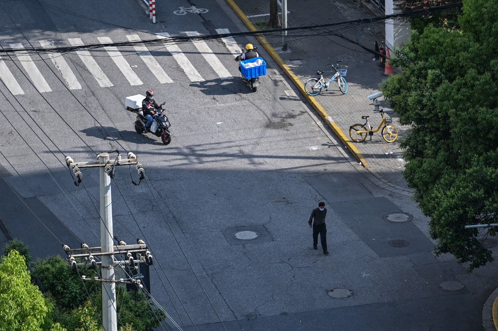 People are seen on a street during a Covid-19 coronavirus lockdown in the Jing'an district, in Shanghai on May 21, 2022. (Photo by Hector RETAMAL / AFP) reopening