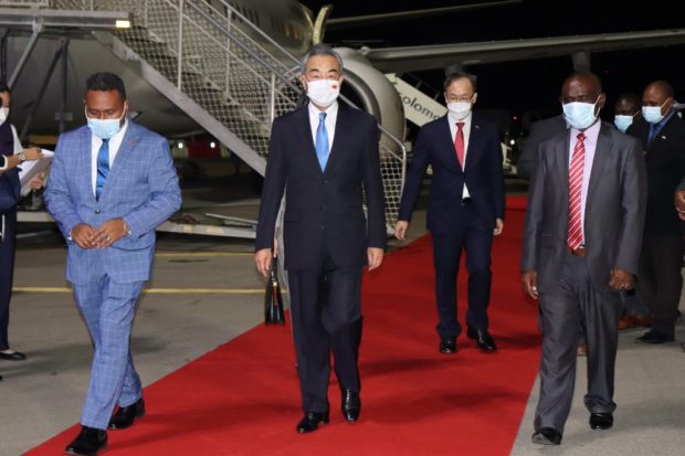 This picture taken on May 25, 2022, shows Solomon Island's Foreign Minister Jeremiah Manele (L) and Chief Protocole Walter Diamana (R) escorting Chinese Foreign Minister Wang Yi (C) upon his arrival at the Henderson International Airport in Honiara. (Photo by STRINGER / AFP)
