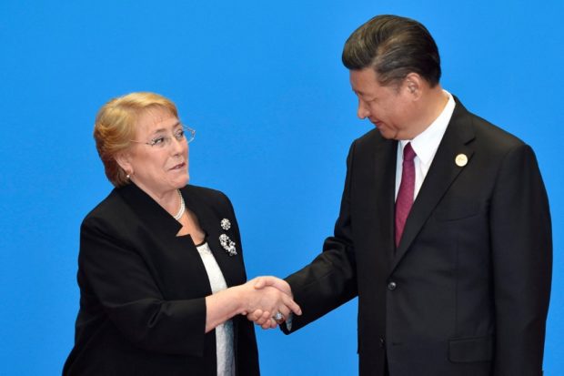 FILE PHOTO Chile's President Michelle Bachelet (L) shakes hands with her Chinese counterpart Xi Jinping during the welcome ceremony for the Belt and Road Forum, at the International Conference Center in Yanqi Lake, north of Beijing, on May 15, 2017. (Photo by Kenzaburo FUKUHARA / POOL / AFP)