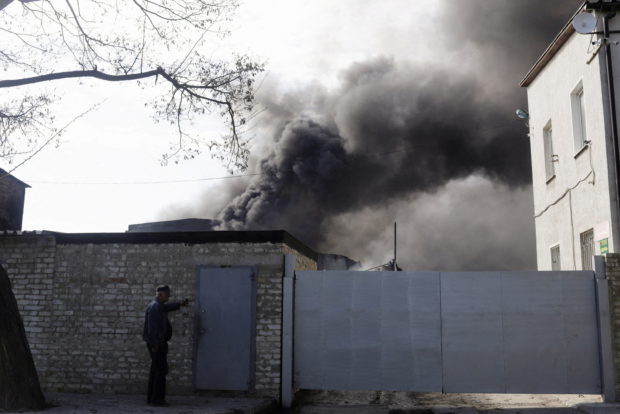 A person rings the bell outside a burning plant, following Russian shelling amid Russia's attack on Ukraine, in Kharkiv, Ukraine, April 30, 2022. REUTERS/Ricardo Moraes