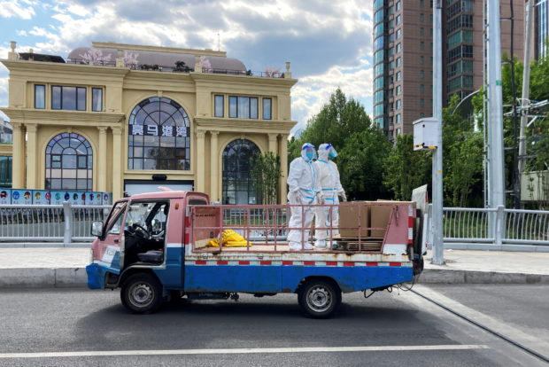 Workers in protective suits stand in a truck on a street amid the coronavirus disease (COVID-19) outbreak, during the Labour Day holiday, in Chaoyang district of Beijing, China May 1, 2022. REUTERS/Martin Pollard