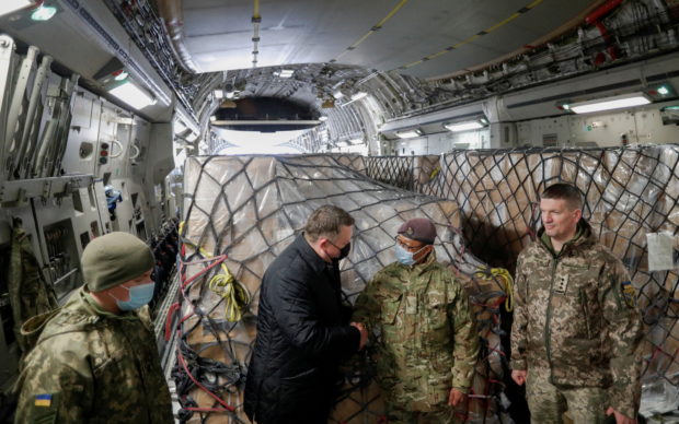 FILE PHOTO: Officials, including British and Ukrainian service members, greet each other before the unloading of a shipment of Britain's security support package for Ukraine, delivered by a C17 Globemaster III aircraft of the Royal Air Force, at the Boryspil International Airport outside Kyiv, Ukraine, February 9, 2022. REUTERS/Valentyn Ogirenko