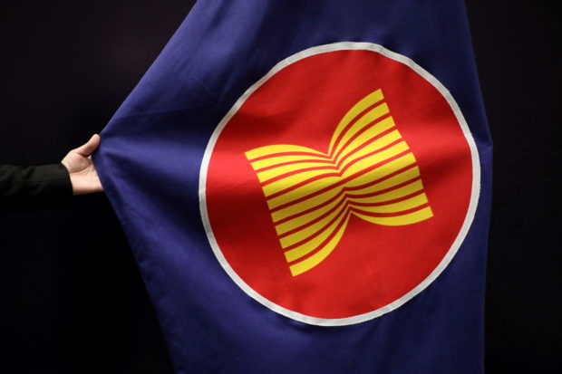 A worker adjusts an ASEAN flag at a meeting hall in Kuala Lumpur, Malaysia, October 28, 2021. REUTERS/Lim Huey Teng