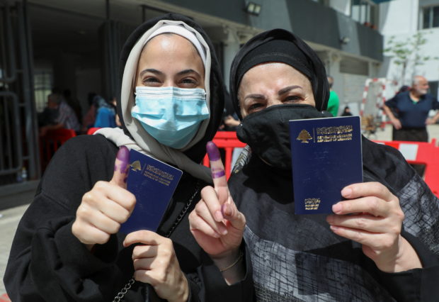Women pose as they hold their Lebanese passports and show their ink-stained fingers after casting their vote in Lebanon's parliamentary election, in Beirut. STORY: Lebanon holds first parliament election since financial collapse