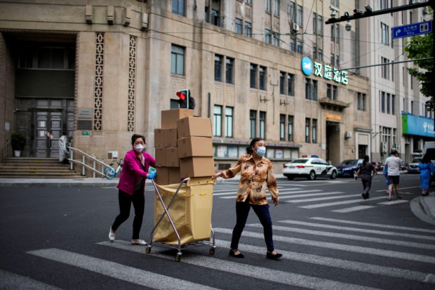 Women carry boxes of food on a street during lockdown, amid the coronavirus disease (COVID-19) outbreak, in Shanghai, China, May 18, 2022. REUTERS/Aly Song