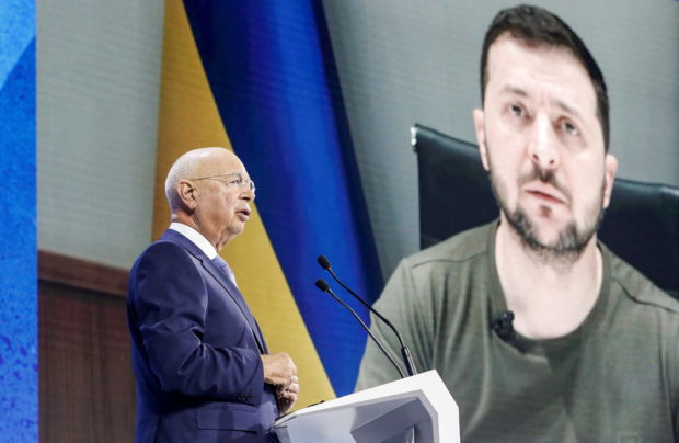 Founder and Executive chairman Klaus Schwab addresses the delegates with the Ukraine's President Volodymyr Zelenskiy displayed on a screen in the background during the opening ceremony of the World Economic Forum (WEF) in Davos, Switzerland May 23, 2022. REUTERS/Arnd Wiegmann