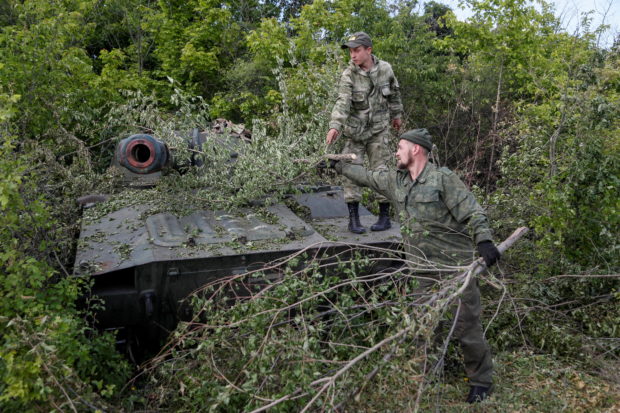Service members of pro-Russian troops remove branches covering a self-propelled howitzer 2S1 Gvozdika at their combat positions in the Luhansk region, Ukraine May 24, 2022. REUTERS/Alexander Ermochenko