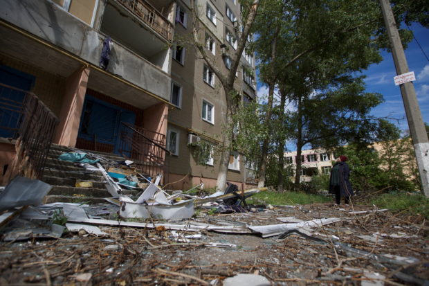 FILE PHOTO: A local woman looks at an apartment building damaged by a Russian military strike, as Russia's attack on Ukraine continues, in the town of Vuhledar, in Donetsk region, Ukraine May 22, 2022. Picture taken May 22, 2022.  REUTERS/Anna Kudriavtseva