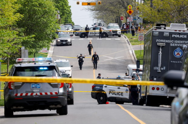 Police officers work at the scene where police shot and injured a suspect who was walking down a city street carrying a gun, as four nearby schools were placed on lockdown, in Toronto, Ontario, Canada, May 26, 2022. REUTERS/Chris Helgren