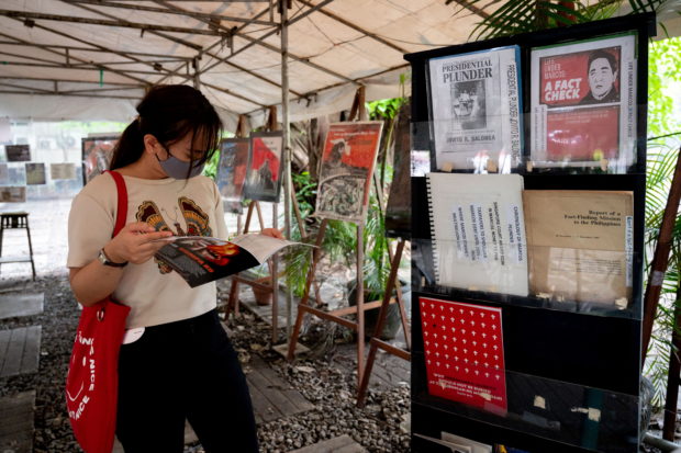 A woman reads a book on martial law under the late dictator Ferdinand Marcos, at the Bantayog ng mga Bayani, in Quezon City, Philippines, May 21, 2022. Picture taken May 21, 2022. REUTERS/Lisa Marie David