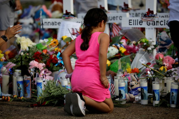 FILE PHOTO: A girl pays respects at the memorial at Robb Elementary school, where a gunman killed 19 children and two adults, in Uvalde, Texas, U.S. May 28, 2022. REUTERS/Marco Bello/File Photo