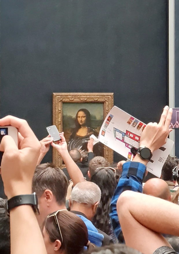 A man tries to wipe off the cake smeared on the protective glass of the painting "Mona Lisa" at the Lourve Museum in Paris, France May 29, 2022 in this screen grab obtained from social media video. Twitter/@klevisl007/via REUTERS
