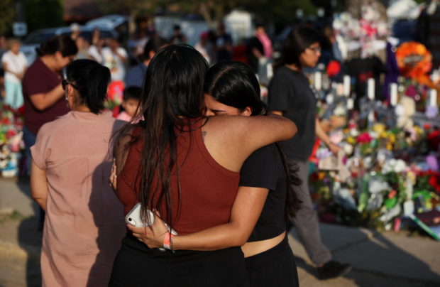 Women embrace as people gather at the memorial at Robb Elementary School, where a gunman killed 19 children and two teachers in the deadliest U.S. school shooting in nearly a decade, in Uvalde, Texas, U.S. May 30, 2022. REUTERS/Shannon Stapleton
