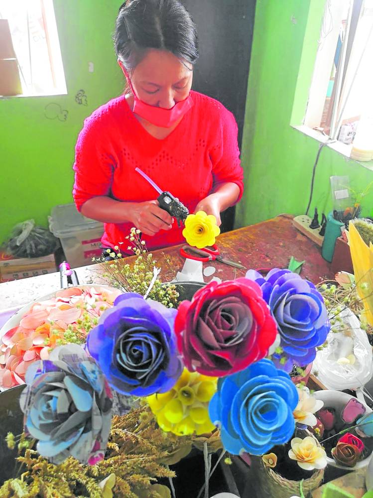 A worker makes flowers out of trash