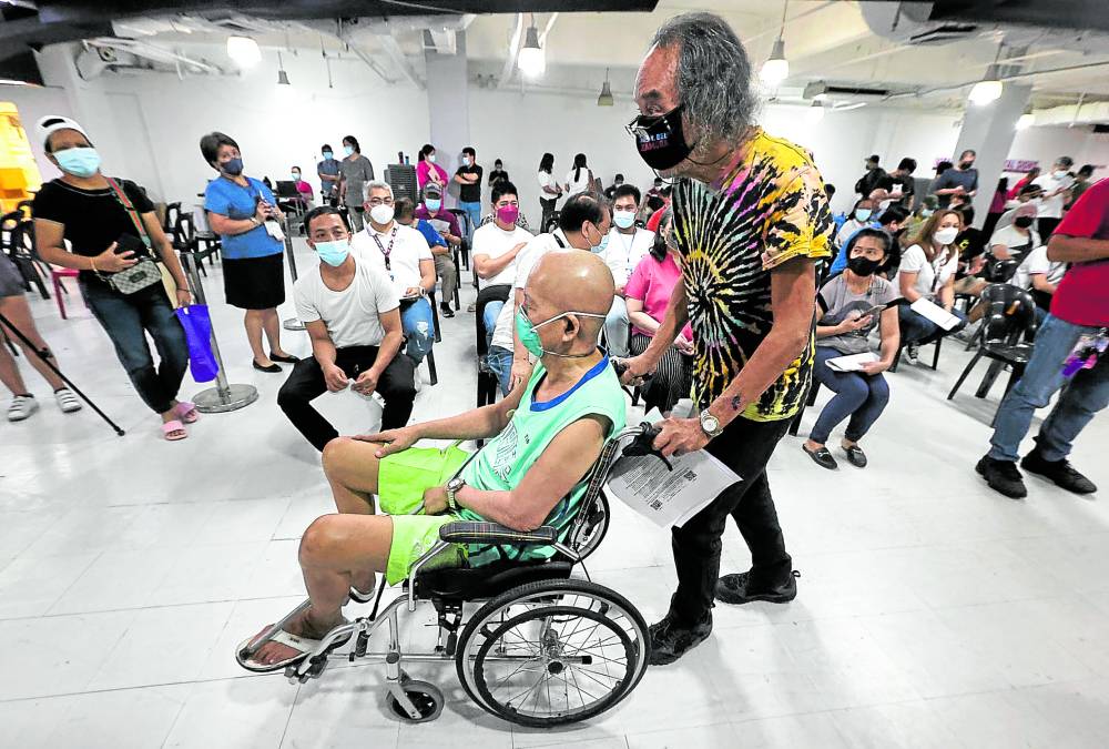 An elderly man is wheeled into a vaccination area inside V-Mall in San Juan City NCR COVID-19 risk reproduction