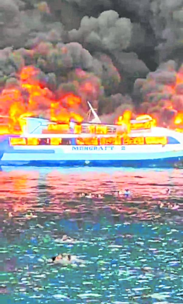 INFERNO Some passengers of MV Mercraft 2 jump into the sea to escape the fire that hit the ferry in Real, Quezon, on Monday. STORY: At least seven people were killed and scores plucked to safety in the Philippines on May 23 after a fire ripped through a ferry and forced passengers to jump overboard, coast guard and witnesses said. (Photo by Handout / Philippine Coastguard / AFP)