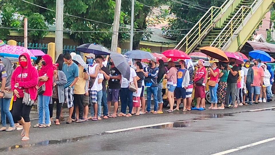 Protected by umbrellas, voters in Barangay Zone 1 in Digos City, Davao del Sur, braved a drizzle to line for ballots. 