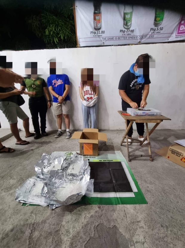 A Philippine Drug Enforcement Agency agent inspects the of shabu that arrived at Clark Freeport as the minor female consignee and her companion look on