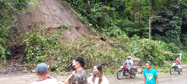 A truck and a motorcycle enter the town of President Roxas and Antipas, Cotabato province, using the cleared portion of the highway after a rockfall and landslide that rendered it impassable for almost an hour on Monday, May 2. WILLIAMOR A. MAGBANUA