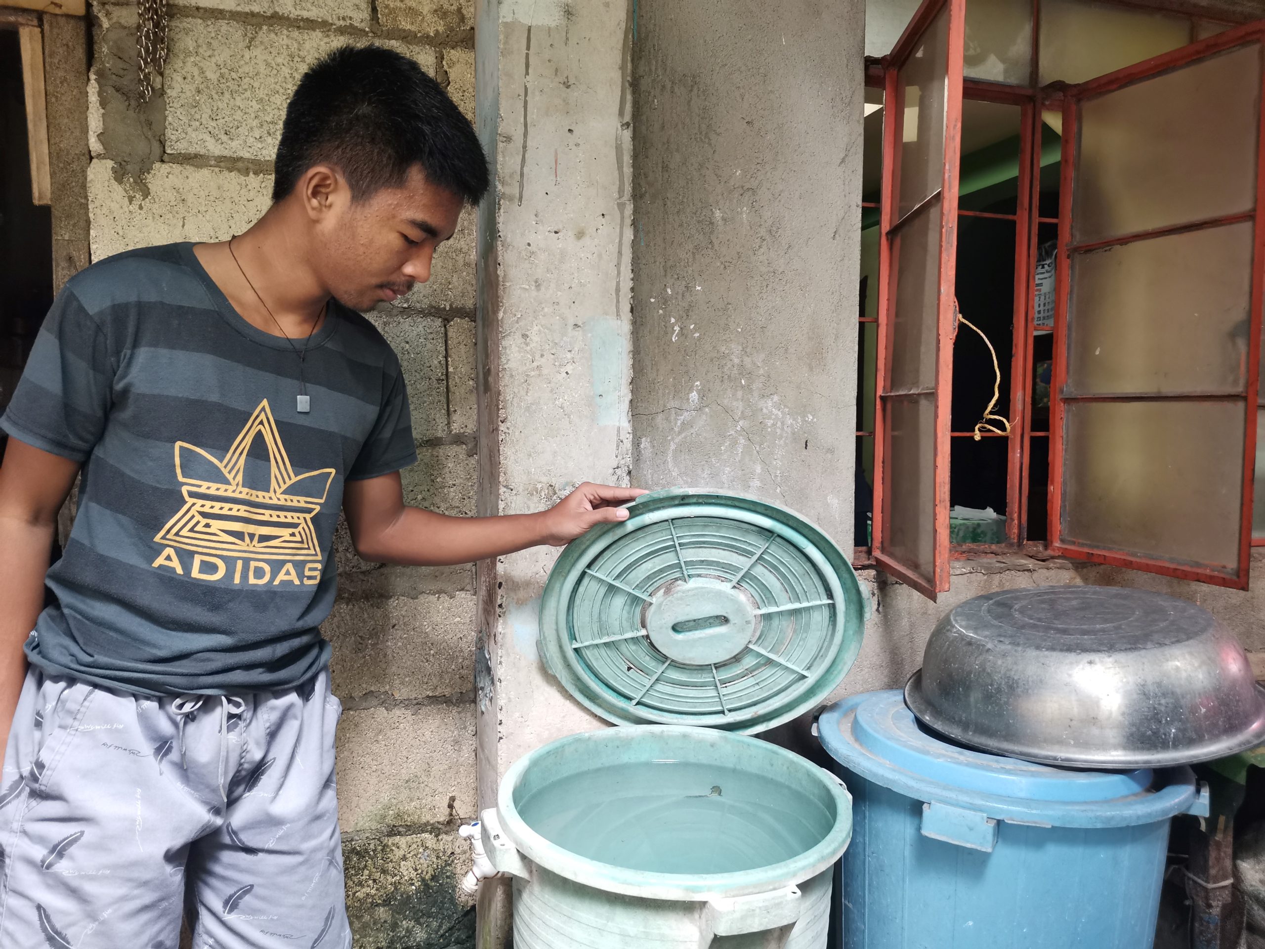 A resident of Tagbilaran City, Bohol makes sure water containers are properly covered to get rid of mosquito breeding sites. 