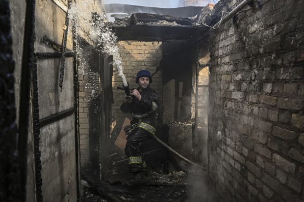 A firefighter extinguishes a burning house hit by Russian Grad rockets in Kyiv's Shevchenkivsky district