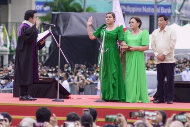 Philippines' Vice President-elect Sara Duterte (C) takes her oath before supreme court associate justice Ramon Hernando (L) and her mother Elizabeth Zimmerman (2nd R) and outgoing president Rodrigo Duterte (R) during the inauguration ceremony near the city hall in Davao City on June 19, 2022. (Photo by Ferdinandh Cabrera / AFP)