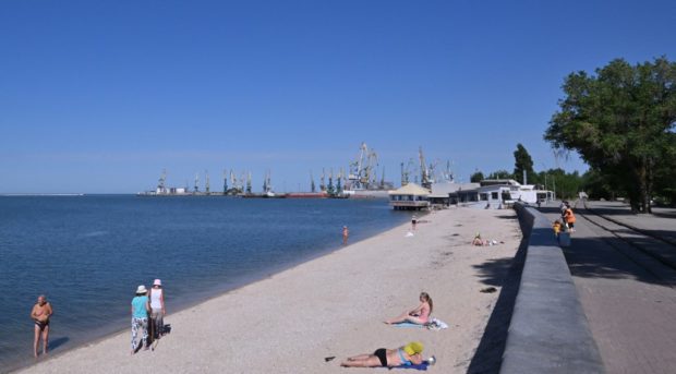 People sunbathe on the beach on the promenade in Berdyansk