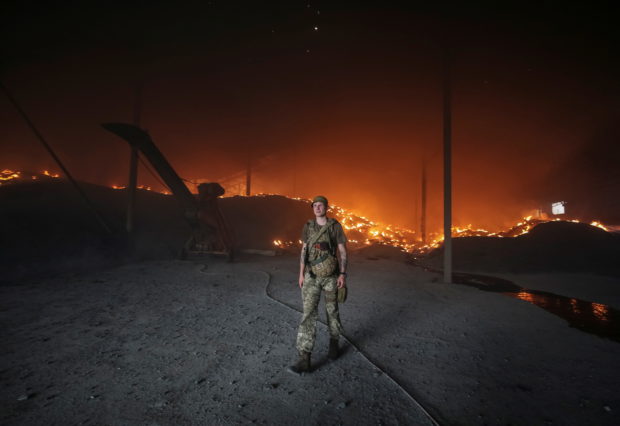 A Ukrainian serviceman walks as seeds burn in a grain silos after it was shelled repeatedly, amid Russia's invasion of Ukraine, in Donetsk region, Ukraine May 31, 2022.  REUTERS/Serhii Nuzhnenko
