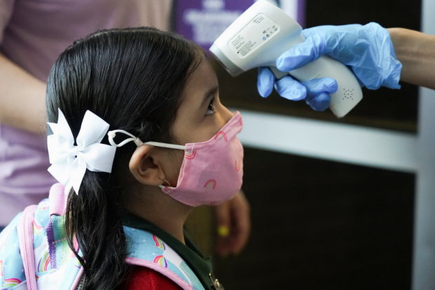 FILE PHOTO: A Pre-K student has her temperature checked before entering Benbrook Elementary School on the first day of school amid the coronavirus disease (COVID-19) pandemic in Houston, Texas, U.S., August 23, 2021.  REUTERS/Go Nakamura/File Photo