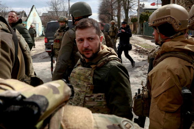 FILE PHOTO: Ukraine's President Volodymyr Zelenskiy looks on as he is surrounded by Ukrainian servicemen as Russia's invasion of Ukraine continues, in Bucha, outside Kyiv, Ukraine, April 4, 2022. REUTERS/Marko Djurica/File Photo