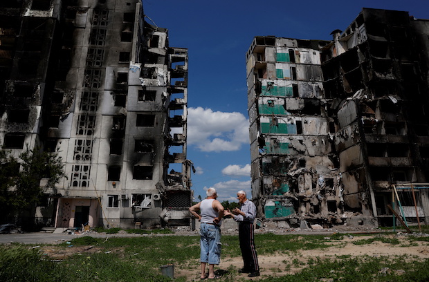 Residents chat in front of a destroyed building in Borodianka. STORY: Russia strikes Kyiv for first time in weeks as battle rages in east