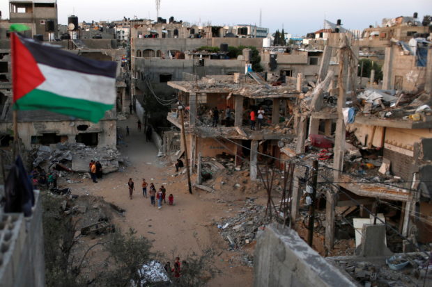 FILE PHOTO: A Palestinian flag flies as the ruins of houses, which were destroyed by Israeli air strikes during the Israeli-Palestinian fighting, are seen, in Gaza Strip, May 25, 2021. REUTERS/Mohammed Salem
