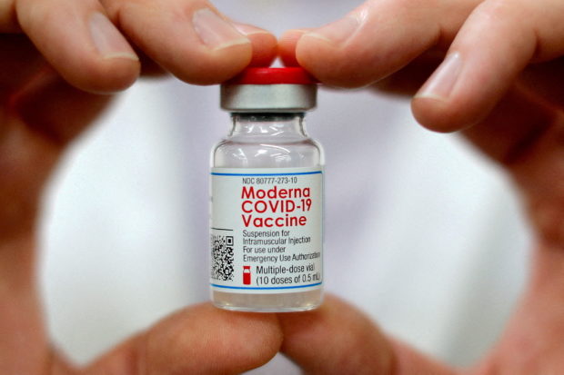 FILE PHOTO: A pharmacist holds a vial of the Moderna coronavirus disease (COVID-19) vaccine in West Haven, Connecticut, U.S., February 17, 2021. REUTERS/Mike Segar