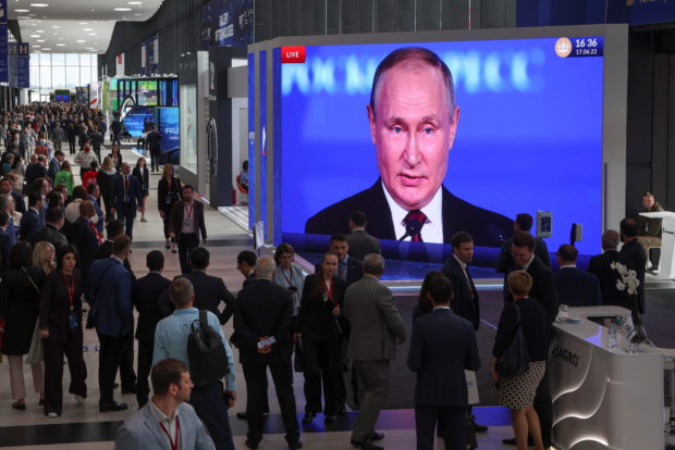 Participants gather near a screen showing Russian President Vladimir Putin, who delivers a speech at the St. Petersburg International Economic Forum (SPIEF) in Saint Petersburg, Russia June 17, 2022. REUTERS/Anton Vaganov