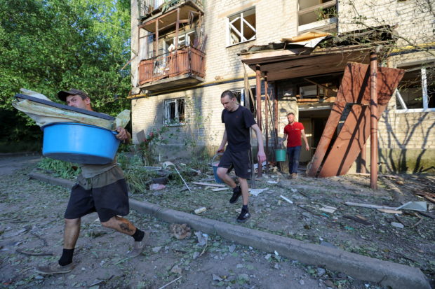 Men walk out of a damaged residential building located in Vannikova street following recent shelling in the course of Ukraine-Russia conflict in Donetsk, Ukraine June 20, 2022. REUTERS/Alexander Ermochenko